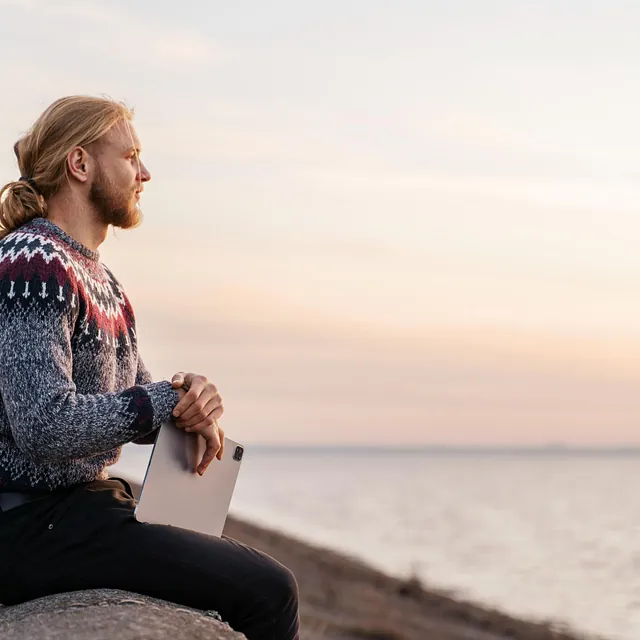 Mann med langt hår og skjegg ser ut over havet